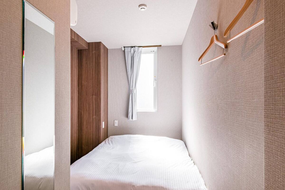 A modern hotel room with a large bed, a mirror, a wooden door, and a window with curtains.