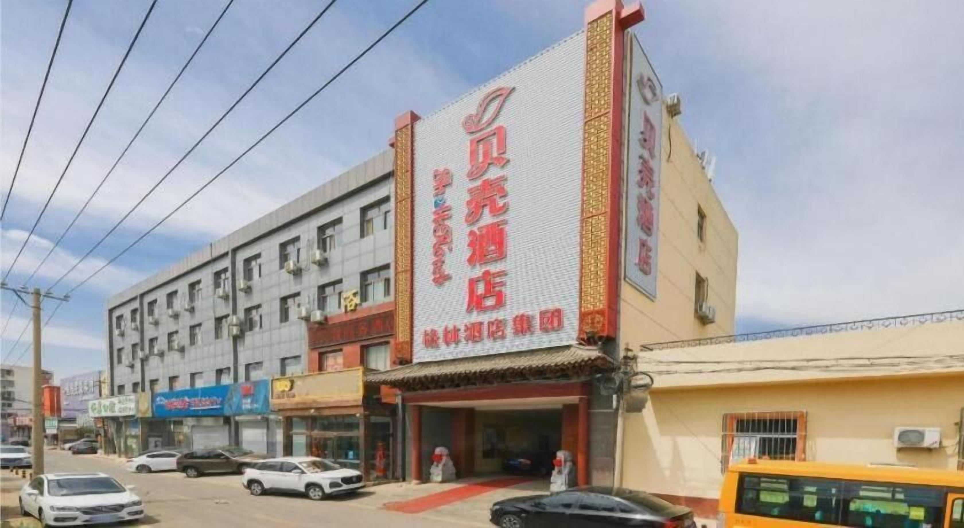 Hotel com grande placa, vários andares e área de estacionamento.