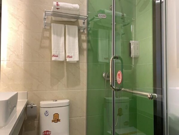 A bathroom with a toilet, a glass shower enclosure, and a towel rack with towels. - Shell Beijing Fangshan Chengguan Metro Station Hotel (Fangshan)
