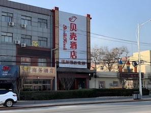 A hotel with a prominent signboard, a modern building facade, and a parked car in front. - Shell Beijing Fangshan Chengguan Metro Station Hotel (Fangshan)