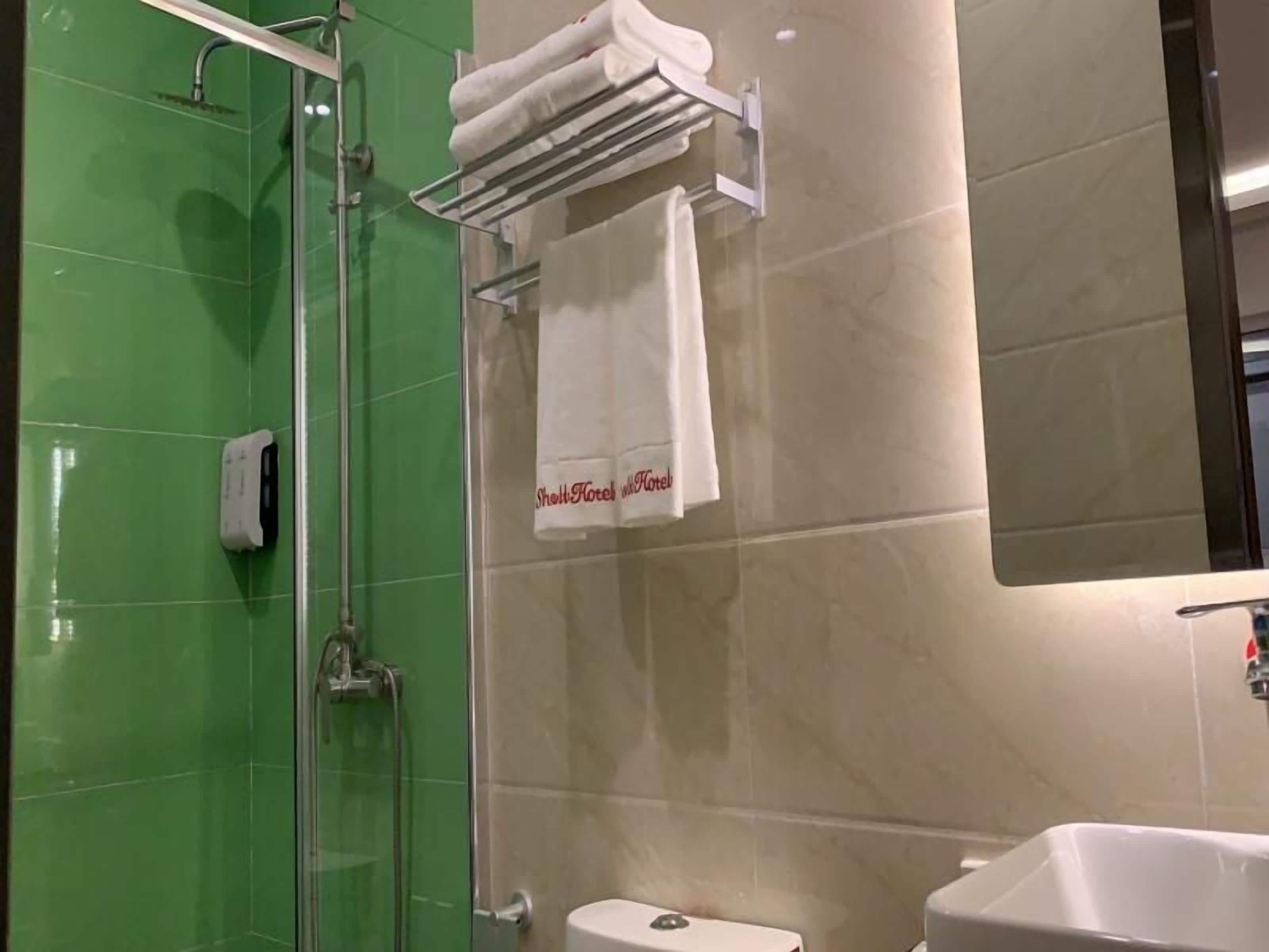 A bathroom with a glass-enclosed shower, a white sink, and a towel rack with a towel hanging on it.