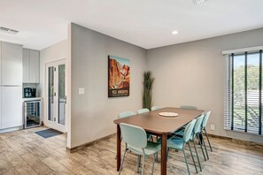 A modern kitchen with a built-in oven and a dining area with a wooden table and light blue chairs. - Upscale Remodel - Walk to ASU; Pool & Pickleball (Tempe)