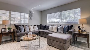 A living room with a sectional sofa, two side tables, a coffee table, and large windows with blinds. - Perfect family Get-Away! (Tampa)