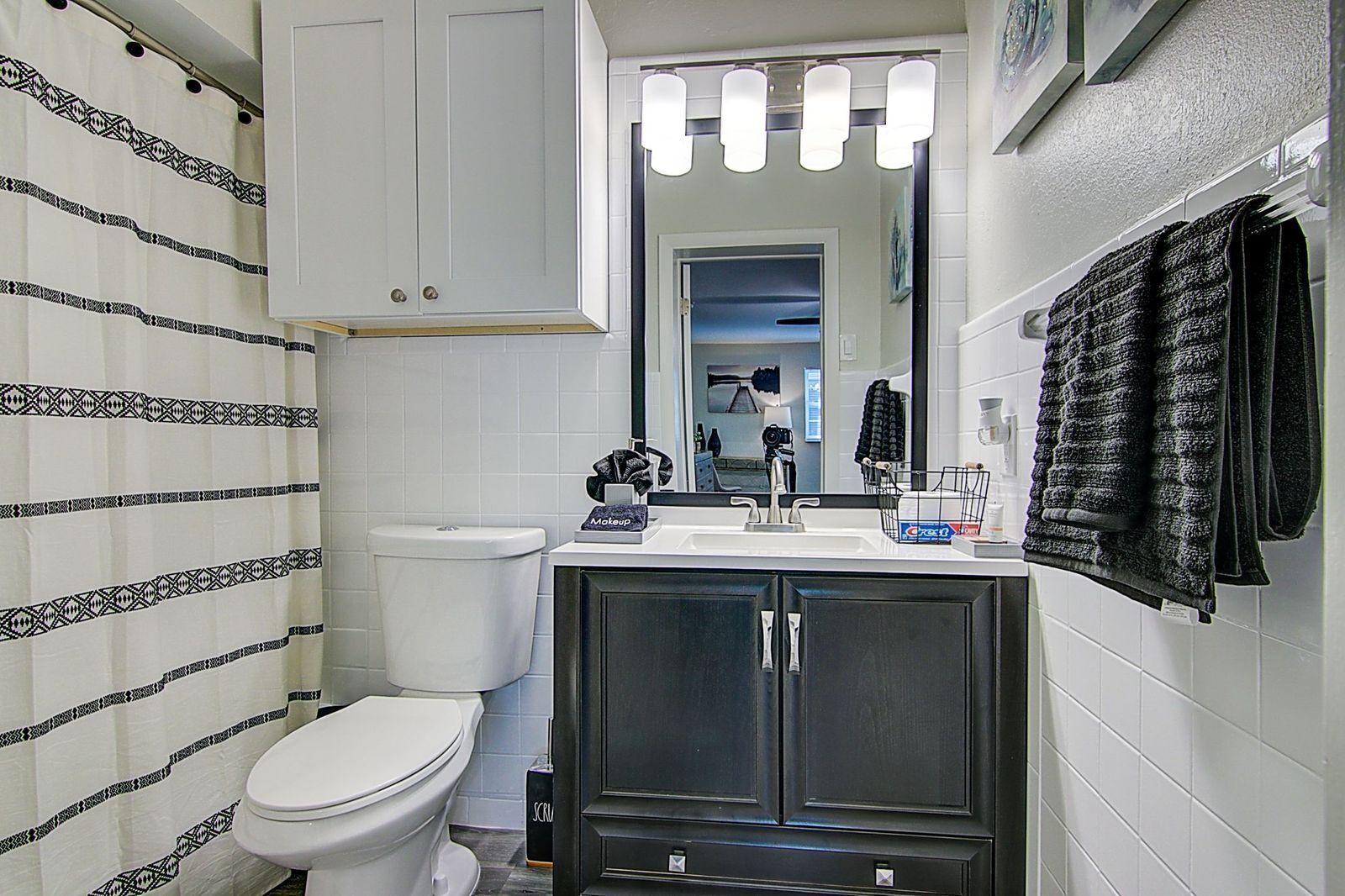 A bathroom with a toilet, a sink with a mirror above it, and a towel rack with towels.
