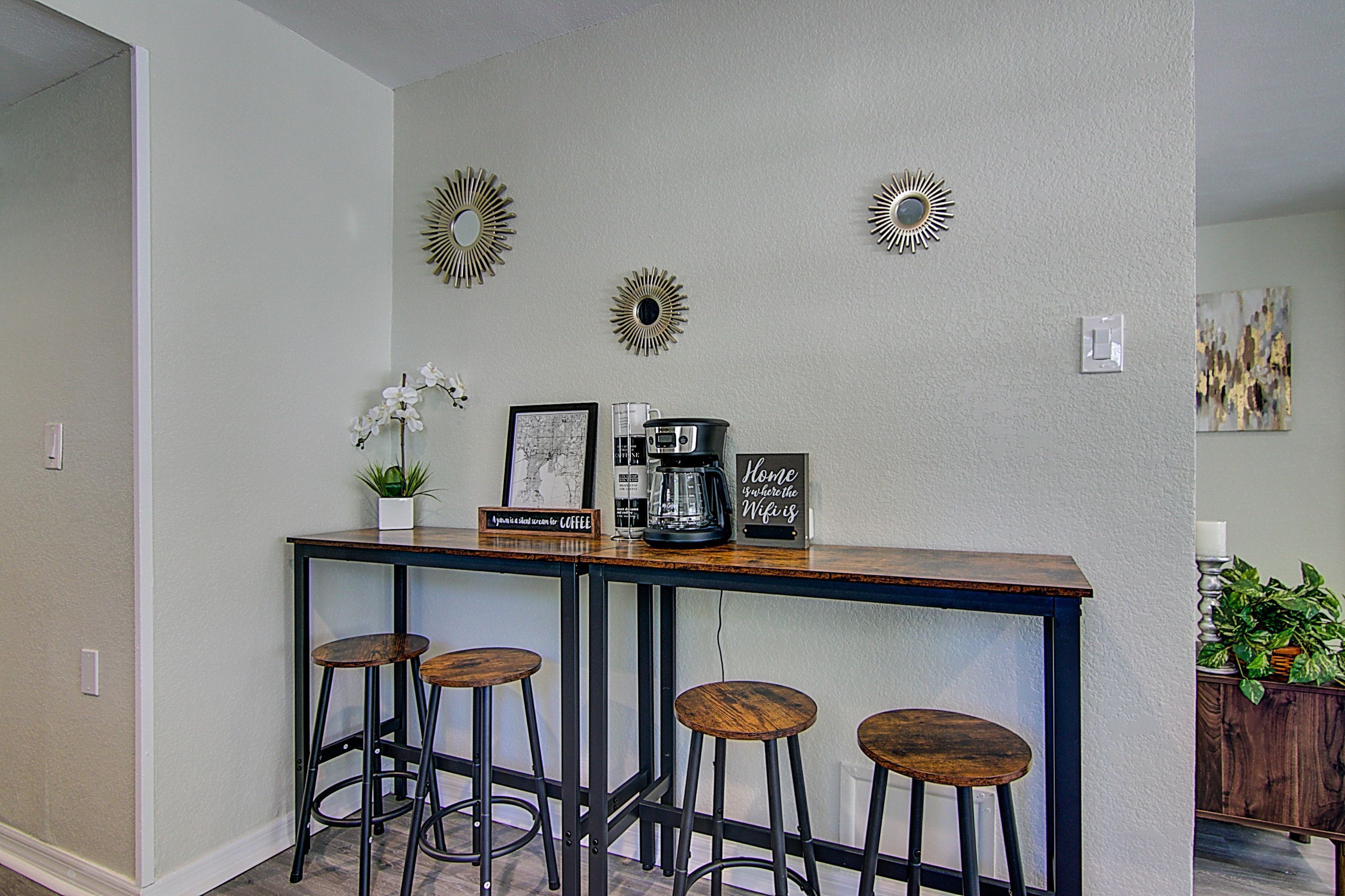 Een bar met een koffieapparaat, ingelijste foto's en decoratieve muurkunst.
