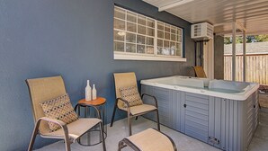 A covered patio area with two chairs, a small table, and a hot tub. - Perfect family Get-Away! (Tampa)
