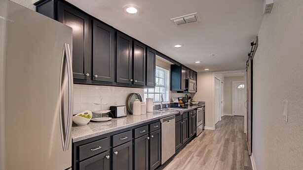 A modern kitchen with dark cabinetry, stainless steel appliances, and a light wood floor. - Perfect family Get-Away! (Tampa)