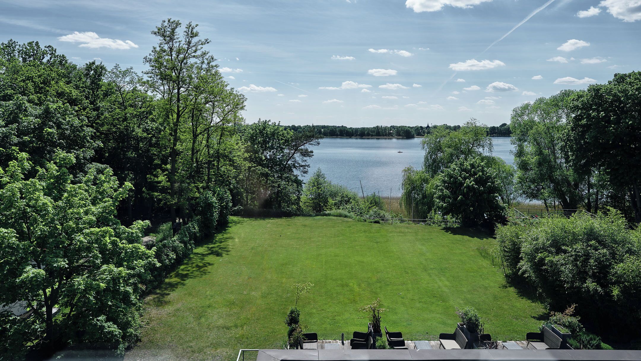 A grassy lawn with a view of a lake and trees.