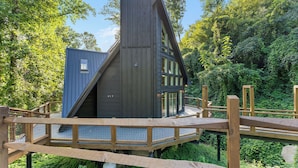 Una casa moderna con un tetto spiovente, ampie finestre e un patio in legno.
