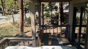 A hot tub on a wooden deck with a view of trees and a building in the background. - Hot Tub | Deck | Fire Pit | BBQ | 2 Living Rooms (Incline Village)