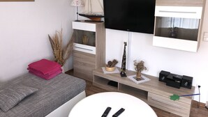 Un salon moderne avec un téléviseur à écran plat fixé au mur, une petite maquette de voilier et une figurine de girafe décorative.