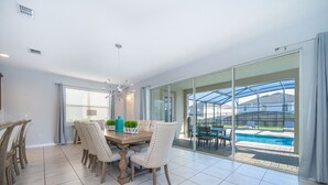 A dining area with a table and chairs, a ceiling fan, and a view of a swimming pool through glass doors. - GB1737 Home 5/5 Private Pool & Jaccuzi, Free Waterpark (Kissimmee)