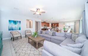 A modern living room with a gray sectional sofa, a wooden coffee table, and a ceiling fan.