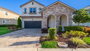 A two-story house with a stone facade, a garage, and a well-maintained front yard with various plants. - GB1737 Home 5/5 Private Pool & Jaccuzi, Free Waterpark (Kissimmee)