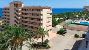 Un hôtel à plusieurs étages doté de balcons, d’un espace piscine et offrant une vue sur la mer.