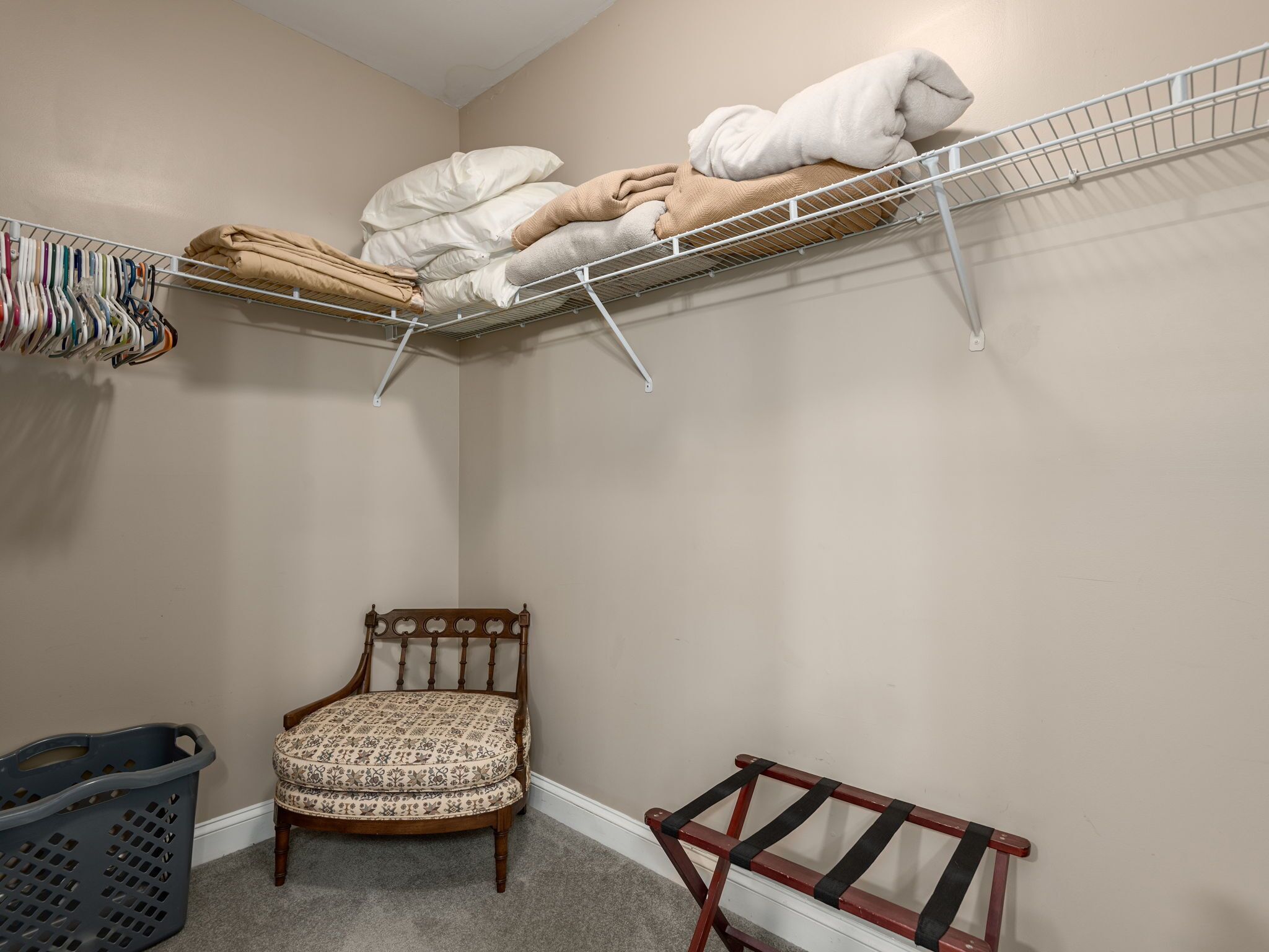 Un espace buanderie comprenant une chaise, un banc et une étagère avec des serviettes et des vêtements pliés.