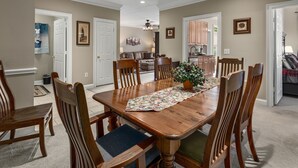 A dining room with a wooden table, chairs, and a floral table runner. - 3's a Birdie - 2BR, 2BA Condo, Golf & Mountain View (Maggie Valley)