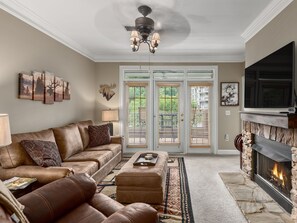 A living room with a fireplace, leather sofa, and artwork. - 3's a Birdie - 2BR, 2BA Condo, Golf & Mountain View (Maggie Valley)