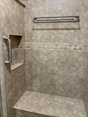 Une douche équipée d’une barre d’appui, d’une étagère et d’un porte-serviettes.