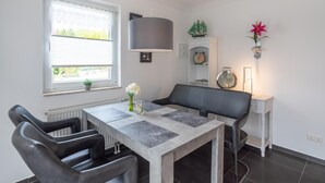 Ein moderner Essbereich mit Tisch, Stühlen, einer Lampe und einem Fenster mit Jalousien.