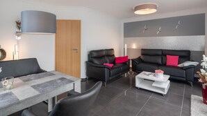 Ein modernes Wohnzimmer mit einer Couch, Sesseln, einem Couchtisch und einem Essbereich.