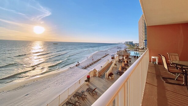Ein Balkon mit Blick auf Strand und Meer bei Sonnenuntergang.
