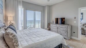 Ein Schlafzimmer mit einem Bett, einem Schminktisch, einem Deckenventilator und Meerblick.