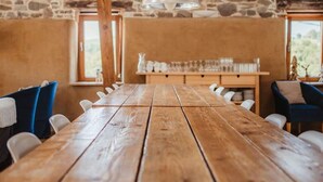 Ein rustikaler Essbereich mit einem Holztisch und -stühlen, einer Steinwand und einer hängenden Leuchte.