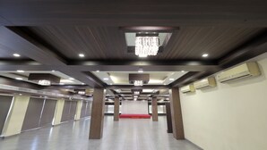 A spacious hotel lobby with a red carpet, multiple air conditioning units, and a chandelier. - HOTEL SHAGUN ROOMS & BANQUET Surat (Surat)