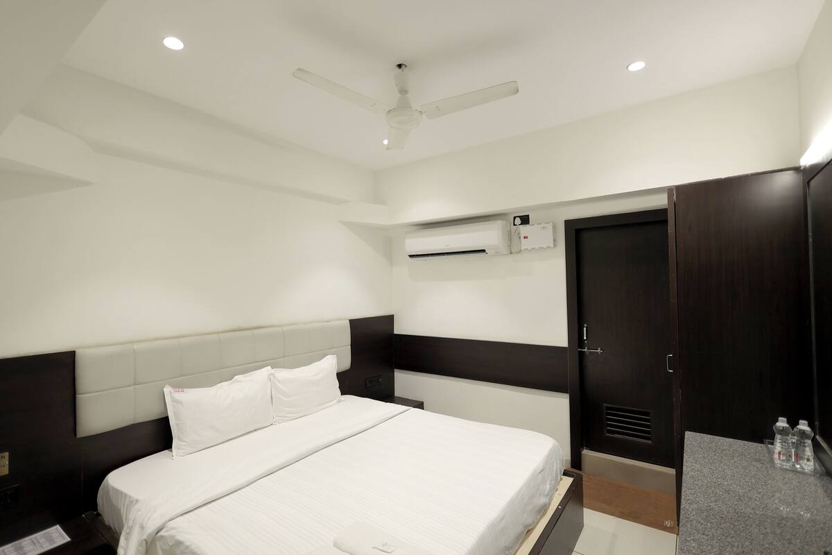Een hotelkamer met een bed, een kledingkast, een nachtkastje en een airconditioning.