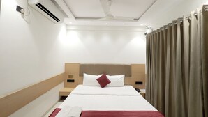 A hotel room with a bed, an air conditioning unit, a ceiling fan, and curtains. - HOTEL SHAGUN ROOMS & BANQUET Surat (Surat)