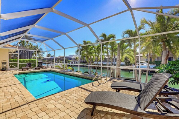 A pool area with a clear view of the water, lounge chairs, and a covered section with a view of the surrounding area.