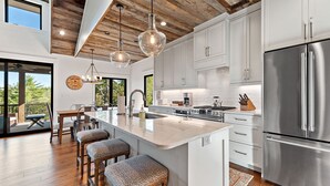 Una cucina moderna con un'isola grande, elettrodomestici in acciaio inossidabile e soffitto in legno.