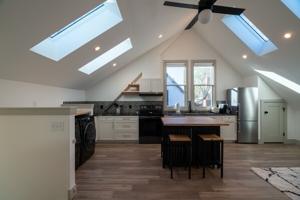 A modern kitchen with skylights, a central island, and a built-in oven. - Guest House | Baker Neighborhood | Walk to Restaurants (Denver)