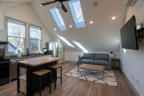 A modern kitchen with a wooden island, a grey sofa, and a ceiling fan. - Guest House | Baker Neighborhood | Walk to Restaurants (Denver)