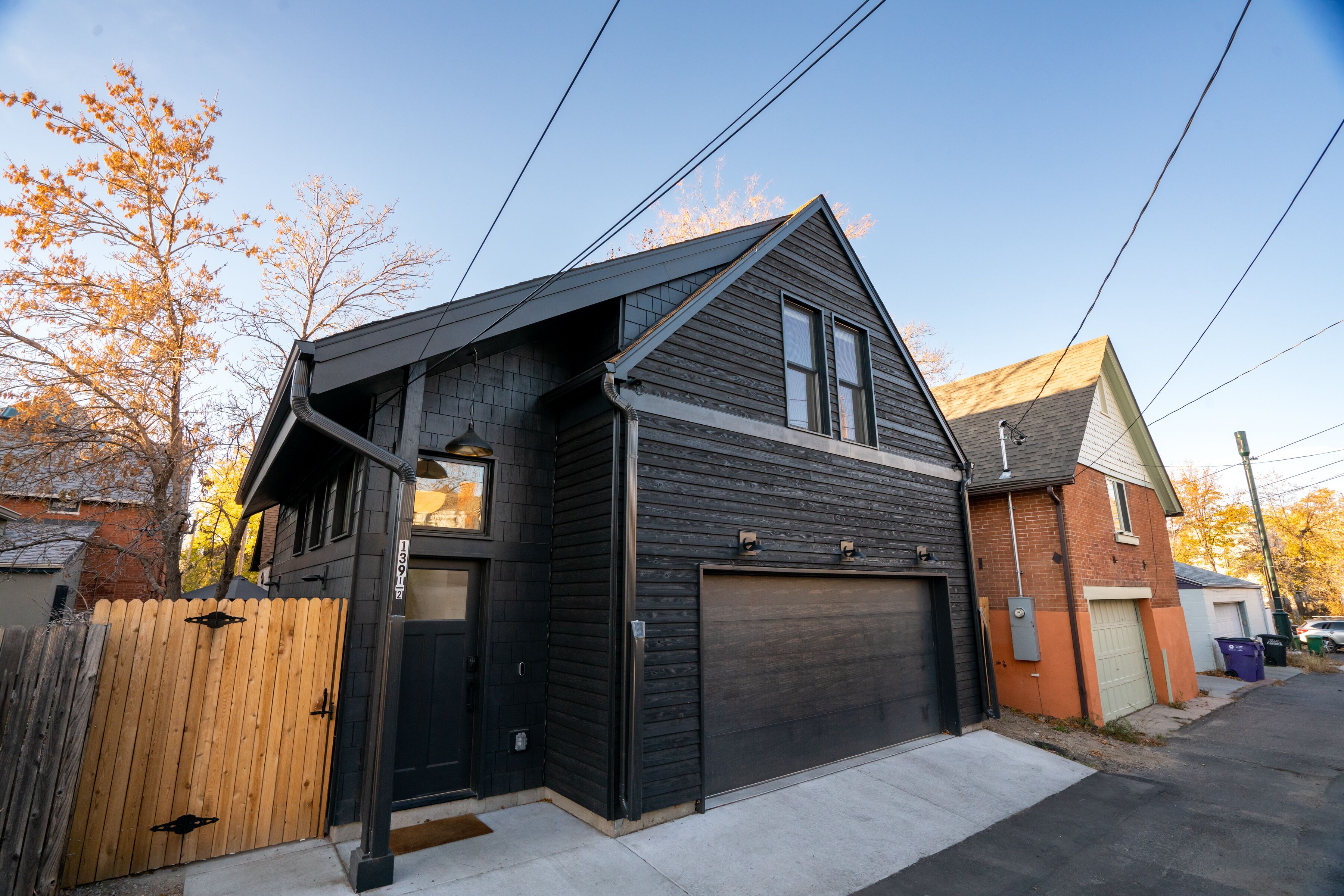 A two-story house with a dark exterior, a garage, and a wooden fence.