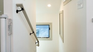 Eine moderne Treppe mit Holzboden und weißen Wänden, die zu einem Raum mit Fenster und einem gerahmten Bild führt.