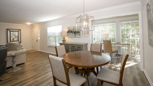 Un coin repas comprenant une table ronde en bois, quatre chaises et un luminaire suspendu.