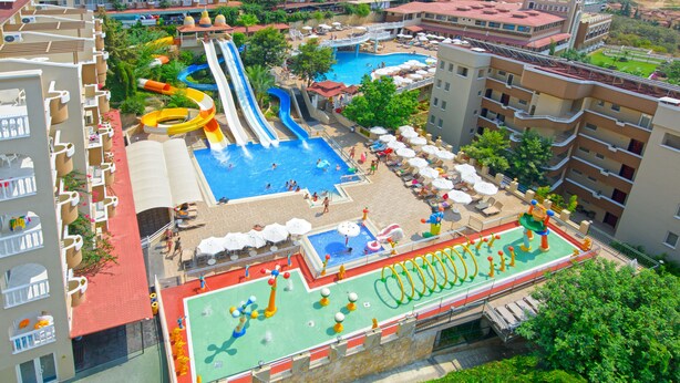 A hotel with a rooftop pool area featuring slides, a children's play area, and outdoor seating.