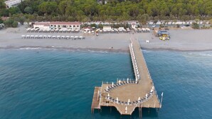 An aerial view of a pier with sun loungers and a beach area with umbrellas and lounge chairs.