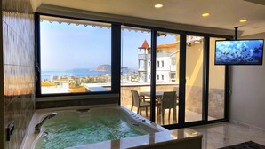 A room with a large window, a bathtub, and a television.