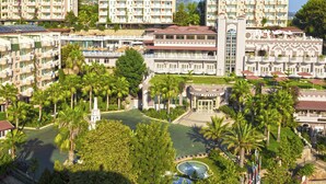 A resort with multiple buildings, a central pool, and lush greenery.