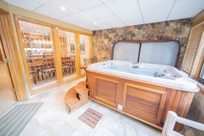 Relax in a serene hot tub area with a bench and table, surrounded by a rustic stone wall.
