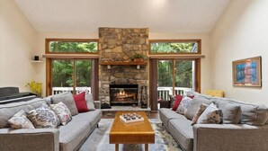 A spacious living room with a stone fireplace, large windows, and a cozy seating area. - Pocono Pines Family Retreat: Game Room, Sunroom & Pets Welcome! (Pocono Pines)