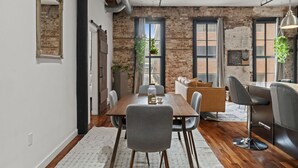 A dining area with a wooden table, grey chairs, and a bar area with a black stool.