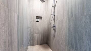 A modern shower with a handheld showerhead and a wall-mounted faucet.