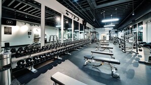 A gym with rows of dumbbells, benches, and weight machines.