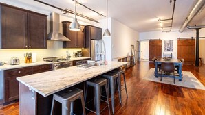 A modern kitchen with dark wood cabinets, stainless steel appliances, and a marble island with bar stools.