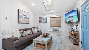 A living room with a sofa, coffee table, and artwork on the walls. - Margate Home w/ Large Outdoor Kitchen (Margate City)