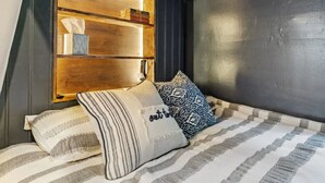 A bed with striped bedding, two pillows, a headboard with shelves, and a dark wall. - Margate Home w/ Large Outdoor Kitchen (Margate City)